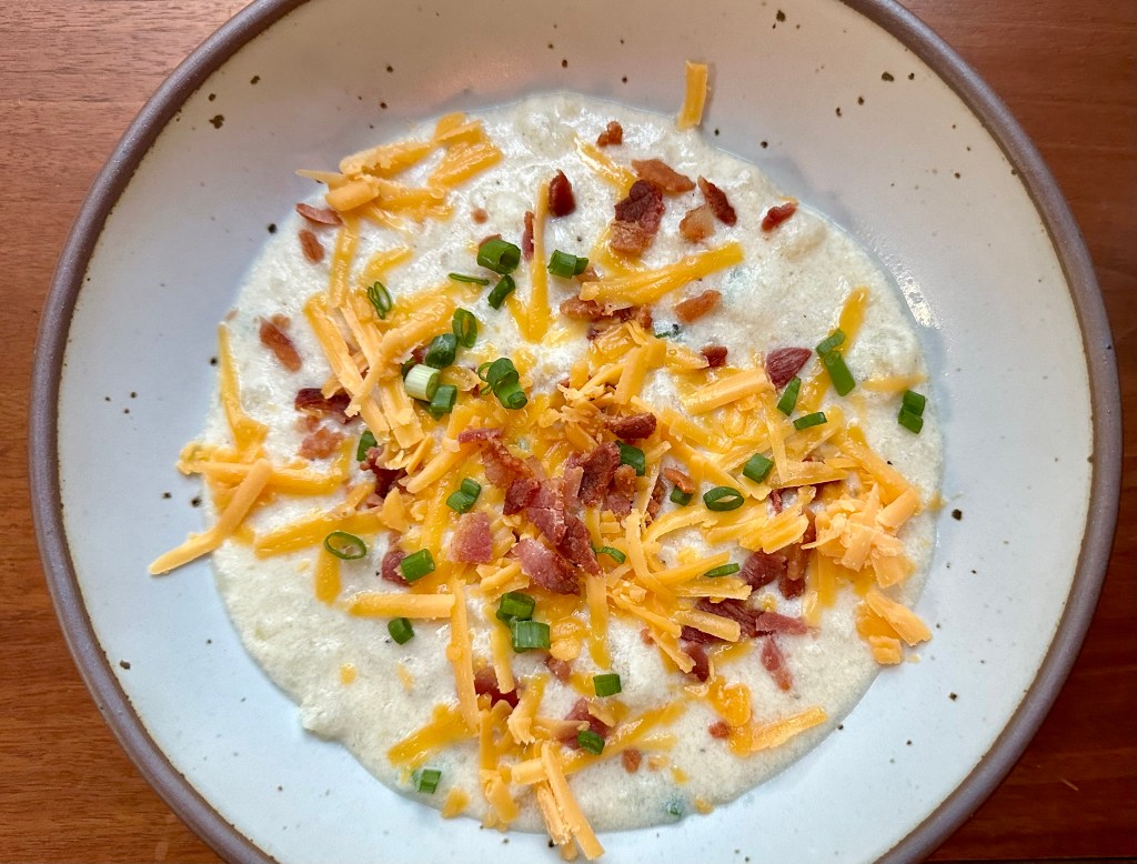Beautiful bowl of potato soup topped with shredded sharp cheddar, crumbled bacon and green onions.