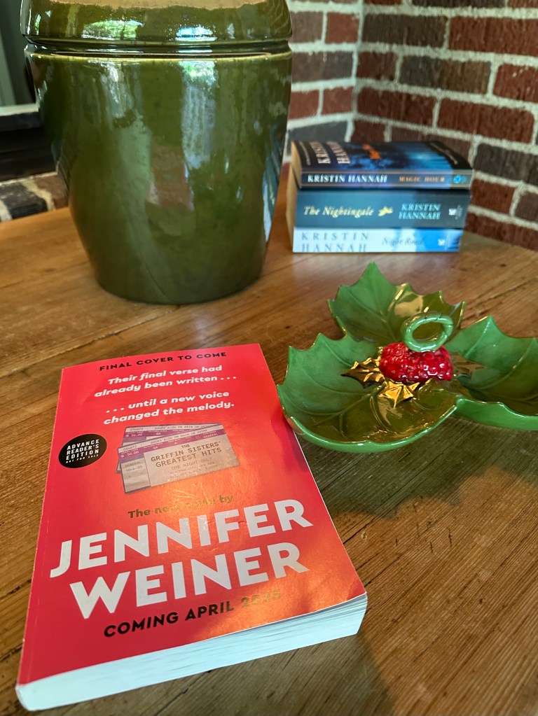 book on table, christmas decoration, stack of books, lamp, the griffin sisters' greatest hits book, jennifer weiner author
