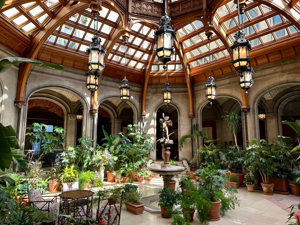 Winter Garden at the Biltmore House, Atrium, Glass ceiling with wood, Stunning electric light fixtures hang from the ceiling, tropical plants, statue, arched openings