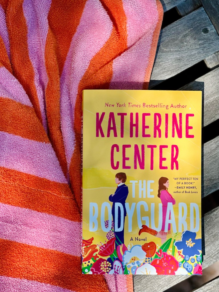 Book, The Bodyguard, by Katherine Center, on beach towel and teak chair