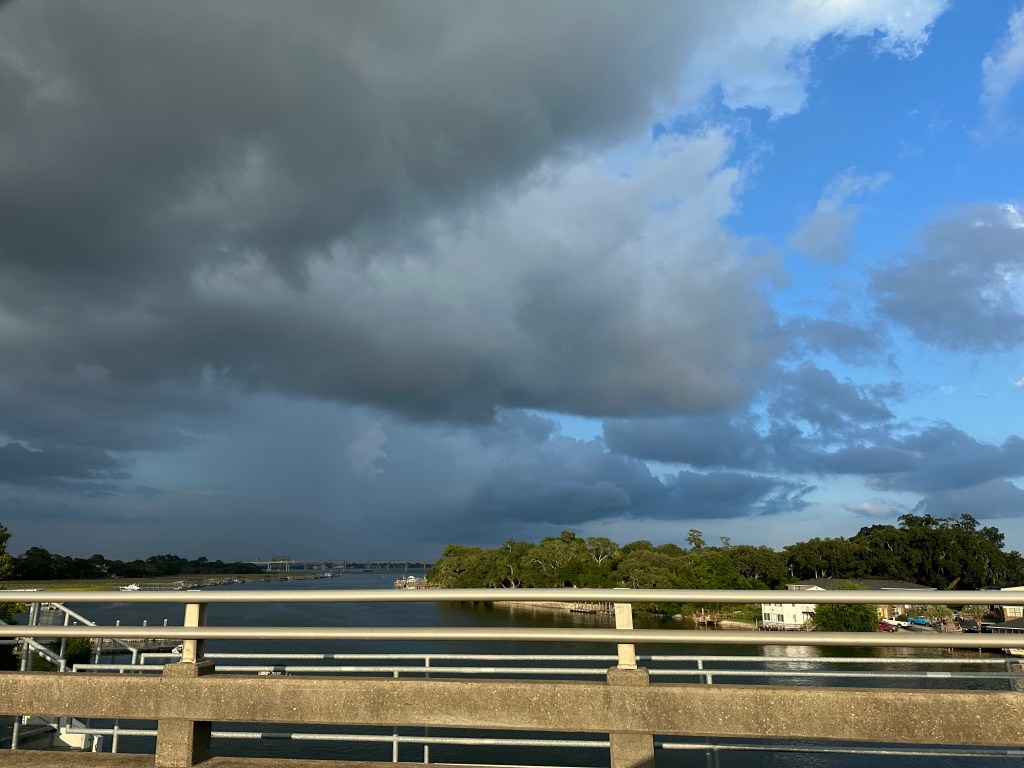 dark stormy sky, intracoastal waterway no boats, side of bridge with sunshine