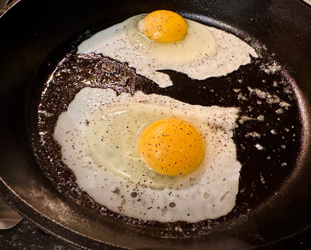 cast iron skillet with two cracked eggs