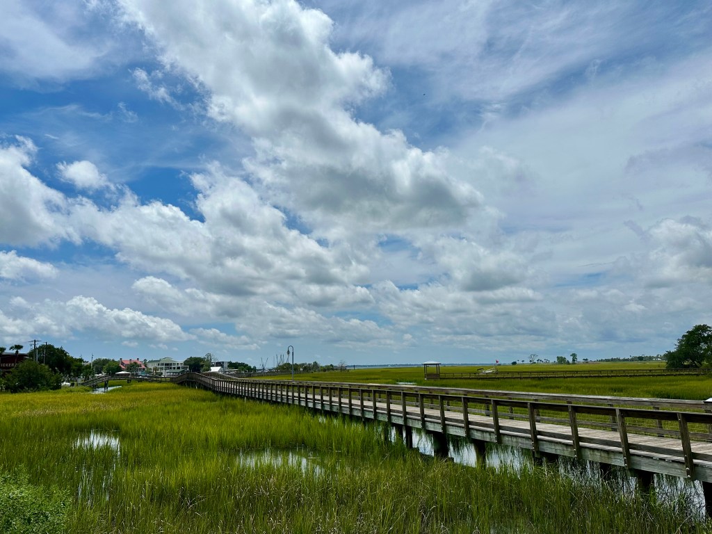 long dock, cloudy blue sky, marsh, water