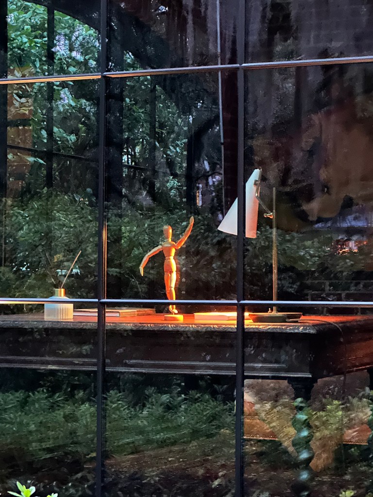 Wooden mannequin in window on a table or desk with lamp